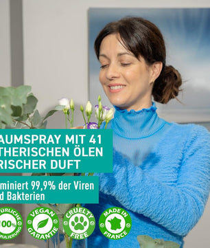 Femme utilisant le spray Puressentiel dans un intérieur fleuri. Élimine 99,9% des virus et bactéries grâce à ses 41 huiles essentielles naturelles.