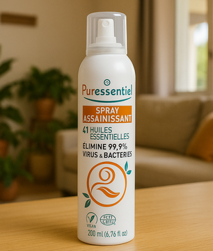 Puressentiel Spray Assainissant - 41 Huiles Essentielles posé sur une table en bois dans un salon lumineux. Purificateur d'air naturel pour maison saine.