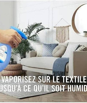 Application du Febreze Spray Textile sur un canapé dans un salon, recommandé jusqu’à humidification du tissu pour une fraîcheur optimale.