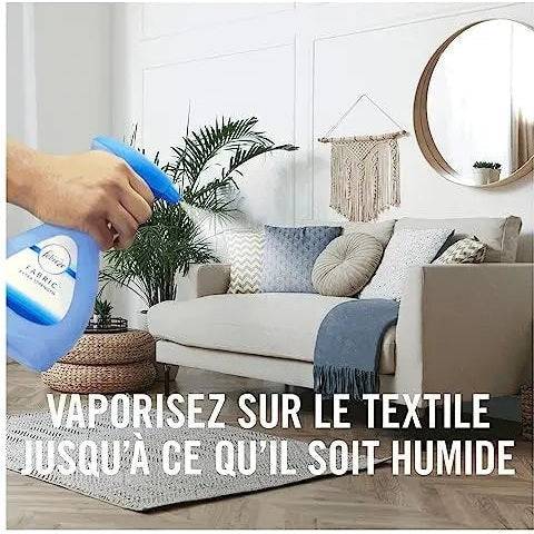 Application du Febreze Spray Textile sur un canapé dans un salon, recommandé jusqu’à humidification du tissu pour une fraîcheur optimale.