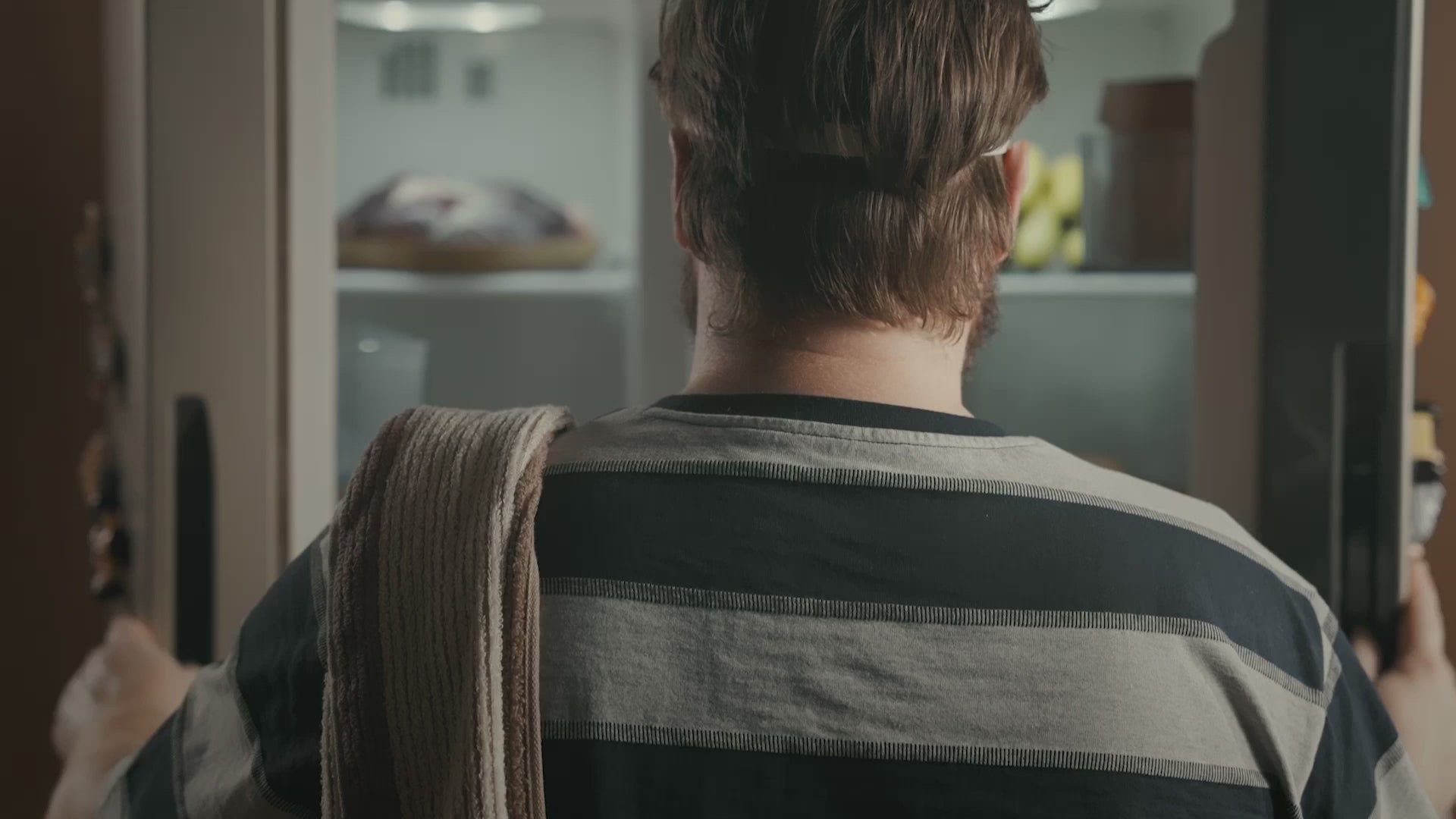 Homme de dos devant un réfrigérateur ouvert, scène de vie quotidienne sans lien direct avec l’aspirateur Ultenic D10.