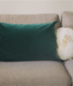 Canapé flou avec coussins colorés. Contexte d'intérieur suggérant l'utilisation du Spray Assainissant Puressentiel pour purifier l'air ambiant.