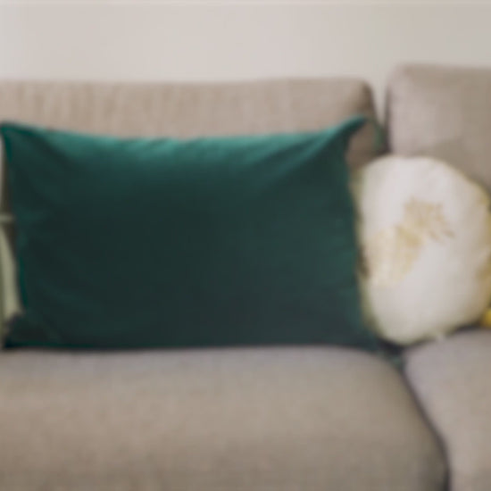 Canapé flou avec coussins colorés. Contexte d'intérieur suggérant l'utilisation du Spray Assainissant Puressentiel pour purifier l'air ambiant.