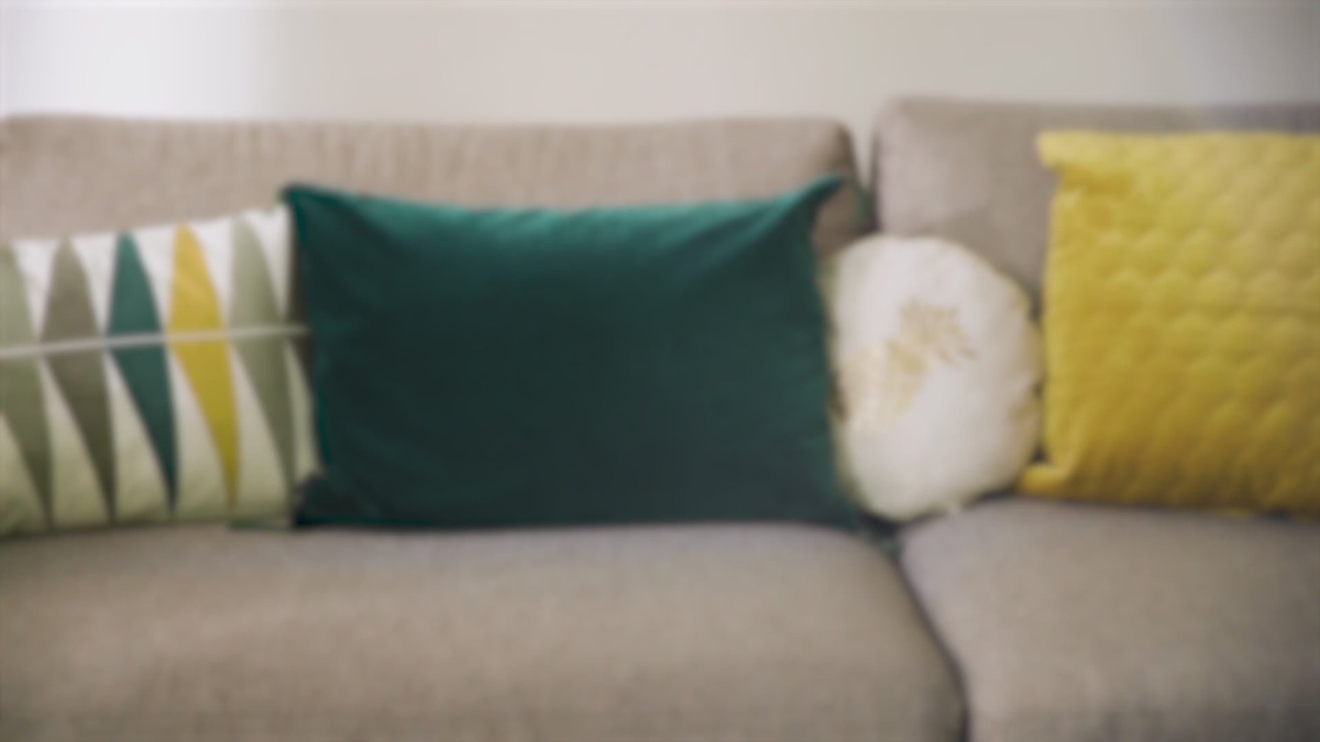 Canapé flou avec coussins colorés. Contexte d'intérieur suggérant l'utilisation du Spray Assainissant Puressentiel pour purifier l'air ambiant.