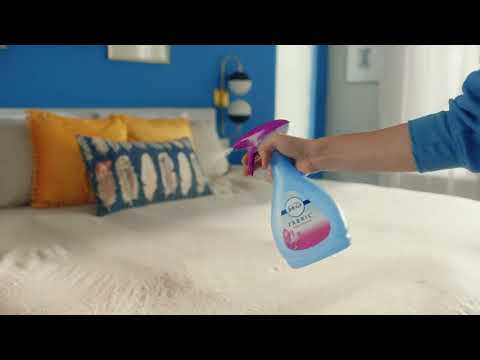 Vaporisation du Febreze Spray Textile sur une literie, illustrant son efficacité pour rafraîchir les tissus avec un parfum Lenor agréable.